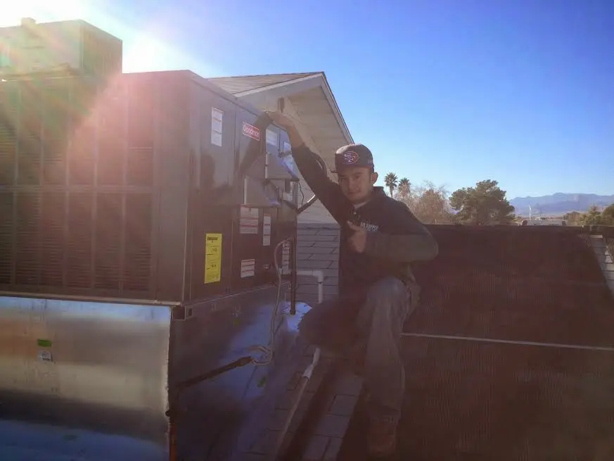 HVAC technician performing Boiler Repair on a rooftop unit in Belmont